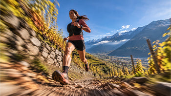 Immagine che raffigura una donna che corre una trail run con la vista di un paesaggio alpestre